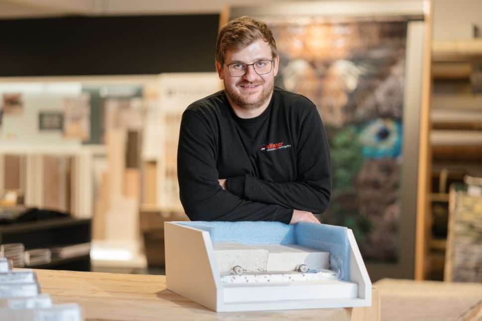 Ein Mitarbeiter im Verkauf präsentiert stolz ein Produkt für den Innenausbau