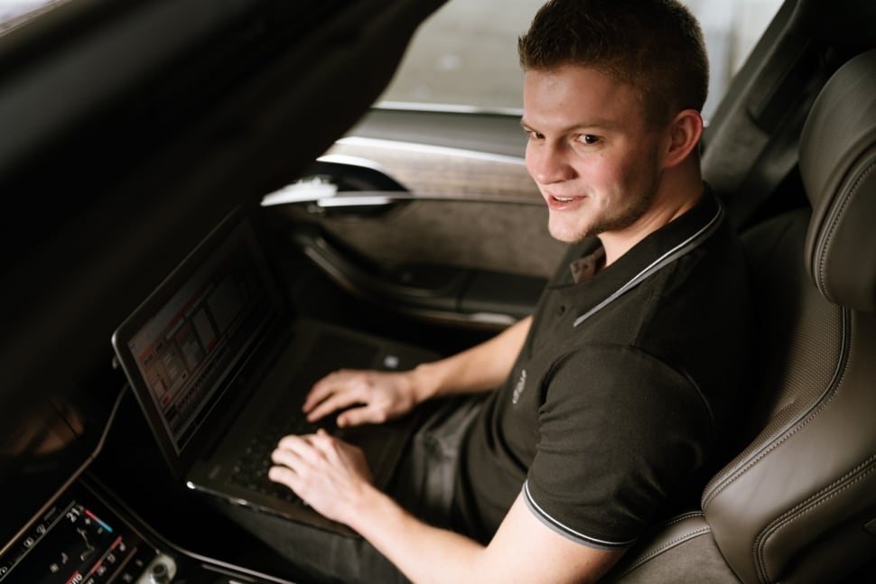 Ein Ingenieur sitzt in einem Audi und führt Messungen mit seinem Laptop durch