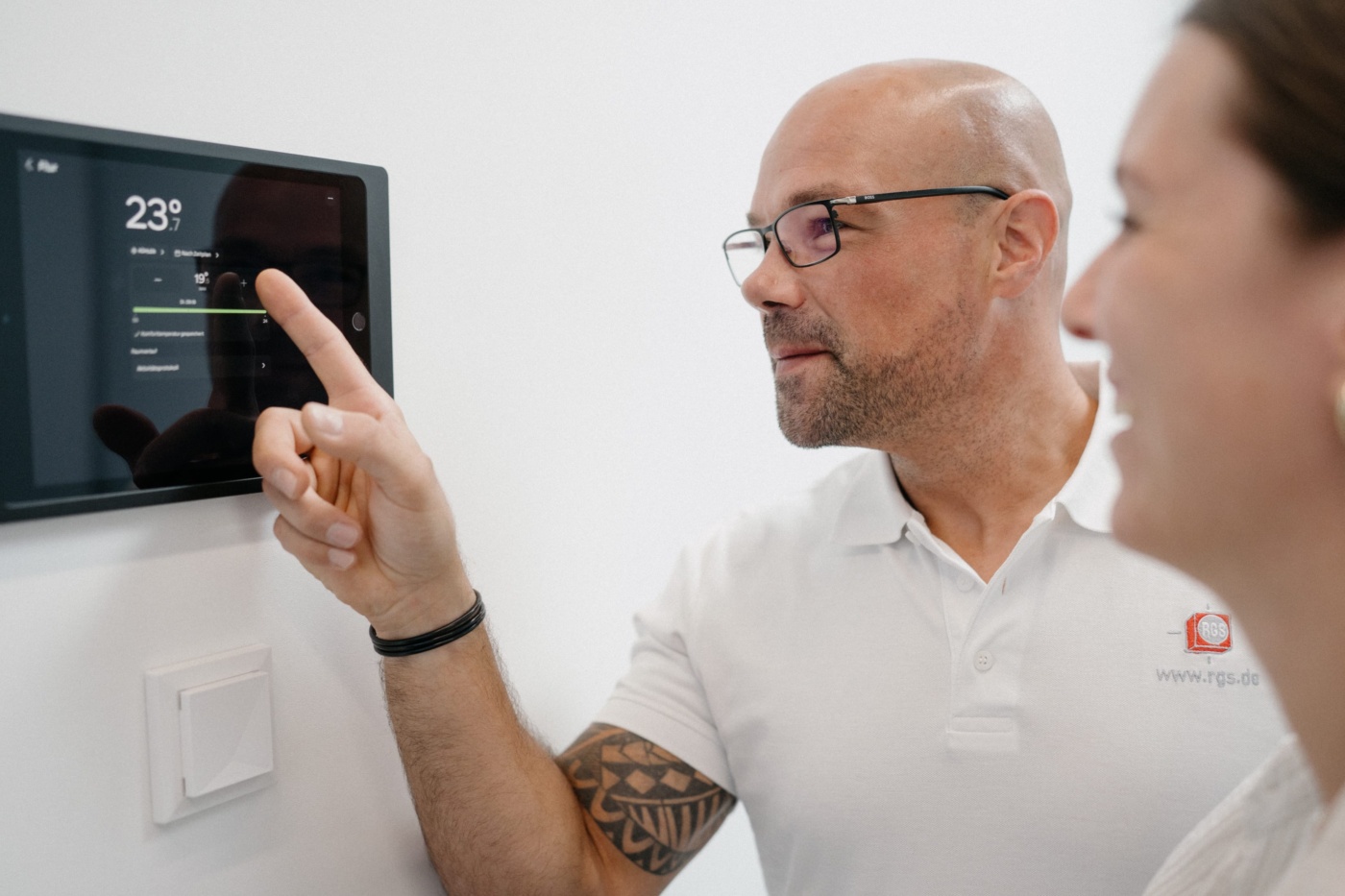 RGS-Mitarbeiter erklärt einer Kollegin die Steuerung einer Klimaanlage am Wanddisplay