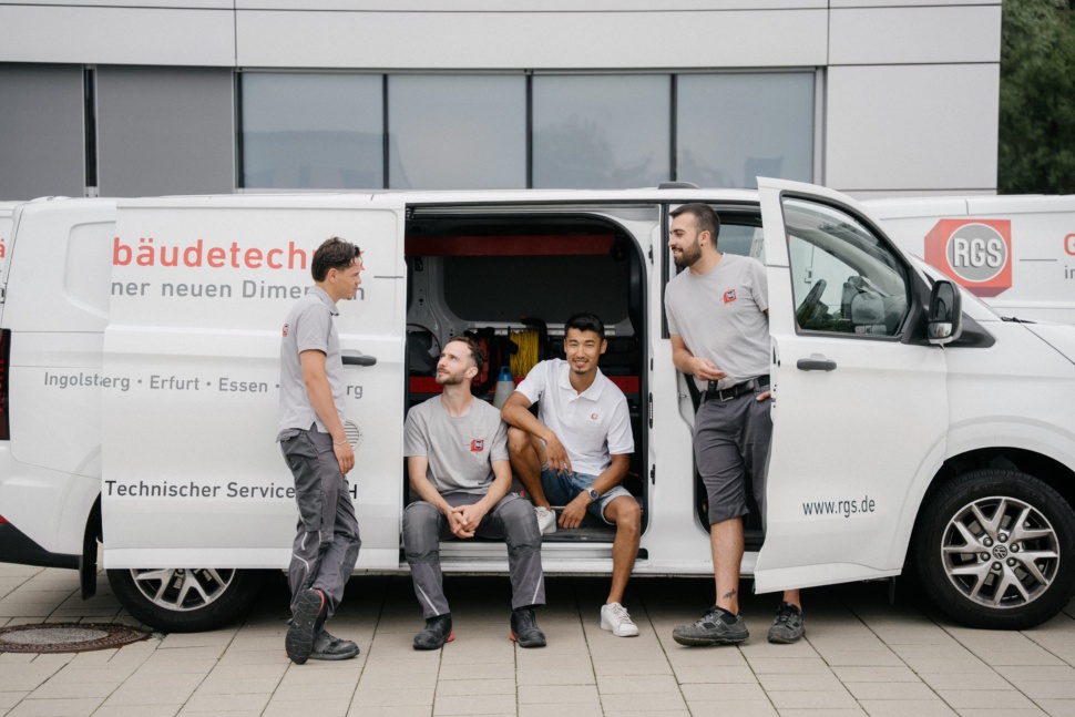 RGS-Monteure machen Pause am Servicefahrzeug vor dem Firmengebäude in Ingolstadt